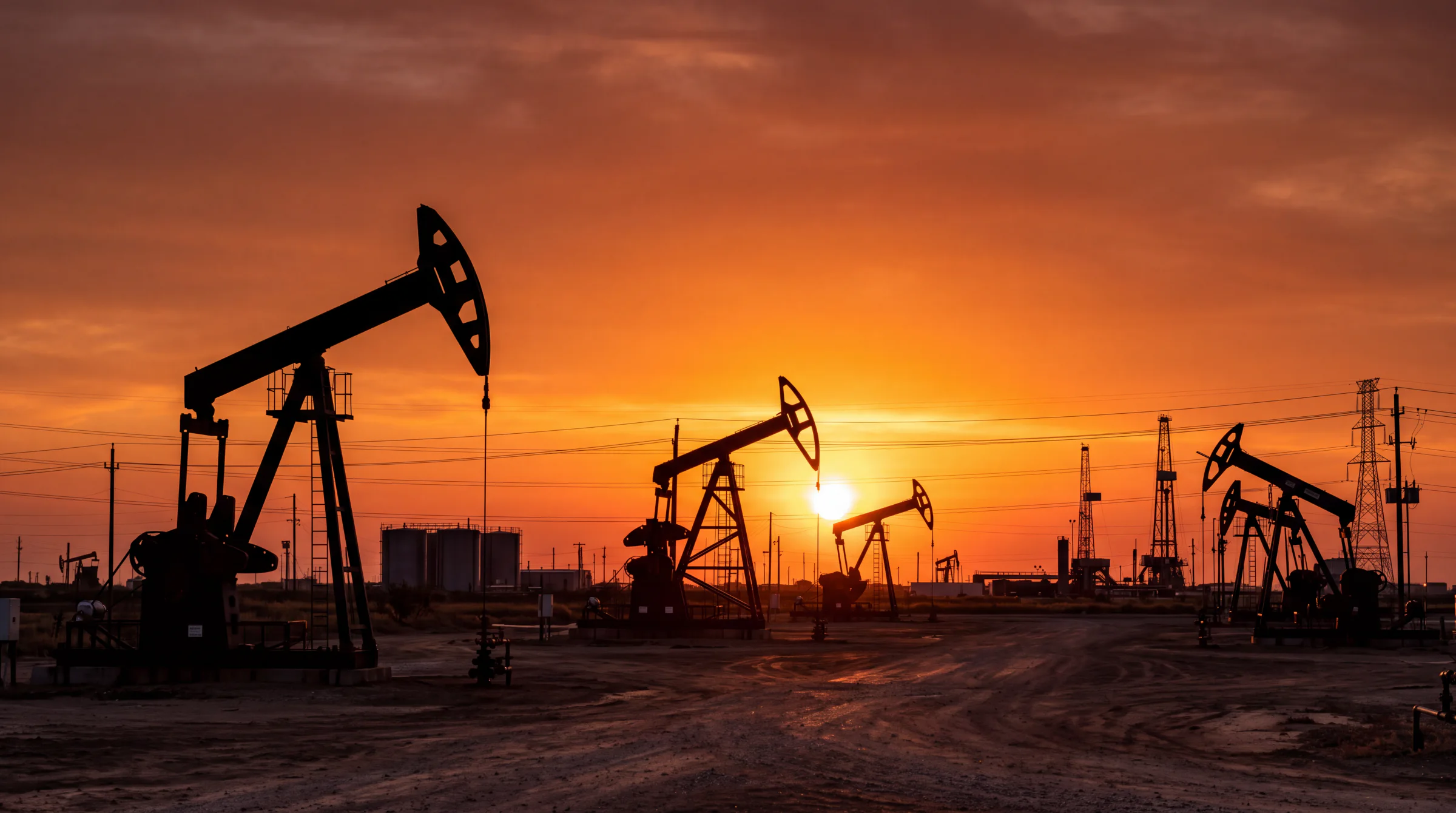 Oil pumpjacks silhouetted against an orange sunset